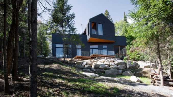 Black Quebec chalet by Atelier Boom-Town overlooks forest and lake .