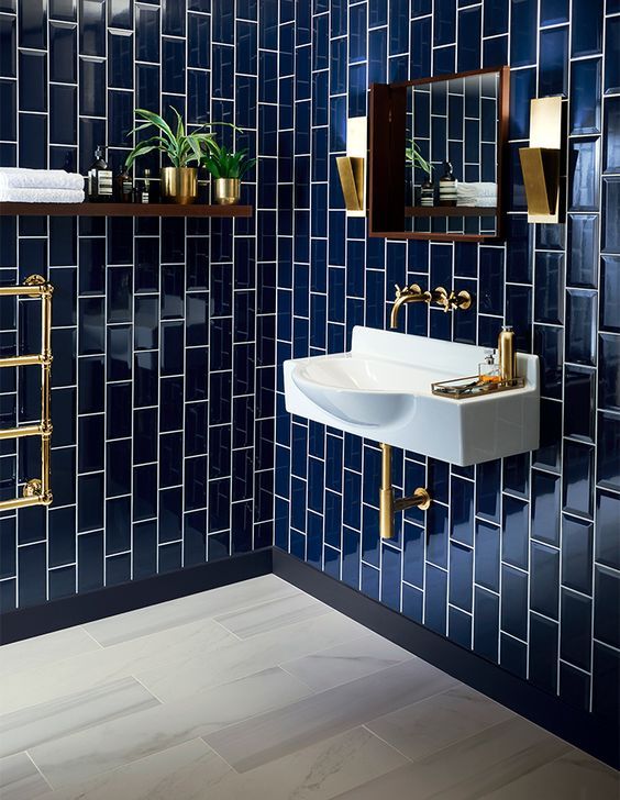 glossy navy tiles clad vertically for a bold art deco bathroom .