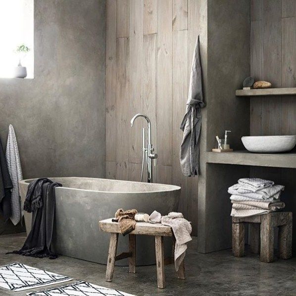 A bathroom with raw materials, like concrete and woodpanels, goes .