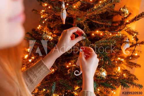 Happy young woman decorating christmas tree at home. Winter .