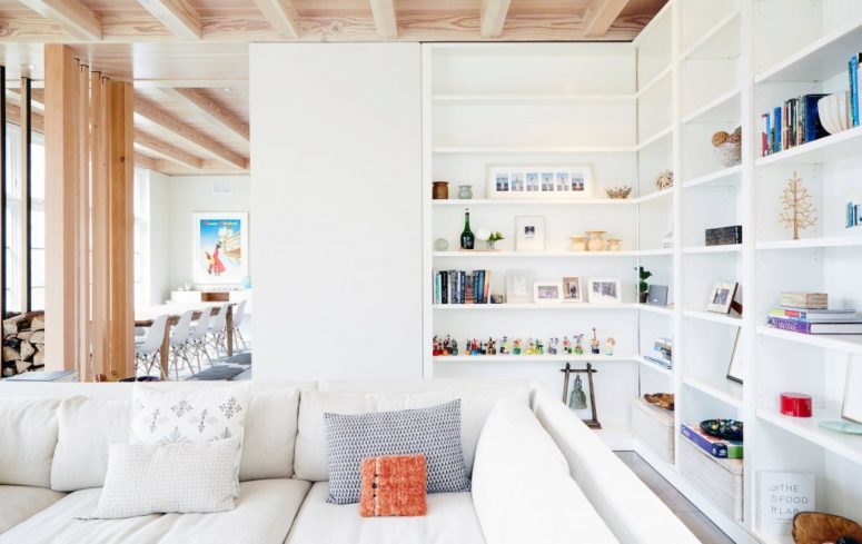 A Sofa With Cushions Placed Near A Big White Bookshelf With Many .
