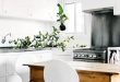 Simple kitchen design with white cabinets, indoor plants and small .