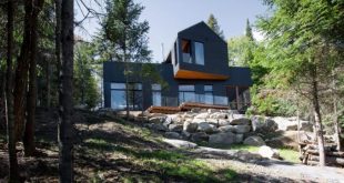Black Quebec chalet by Atelier Boom-Town overlooks forest and lake .