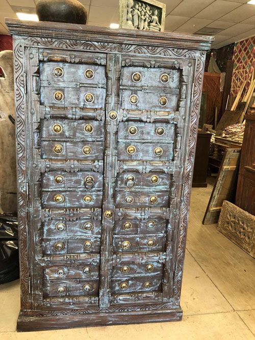 Vintage old carved doors armoire in rustic greens and red patina .