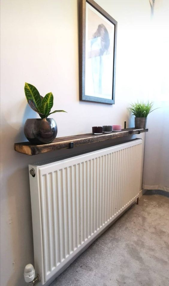 a narrow and long radiator with a dark-stained shelf, candles and potted plants is amazing for a modern space