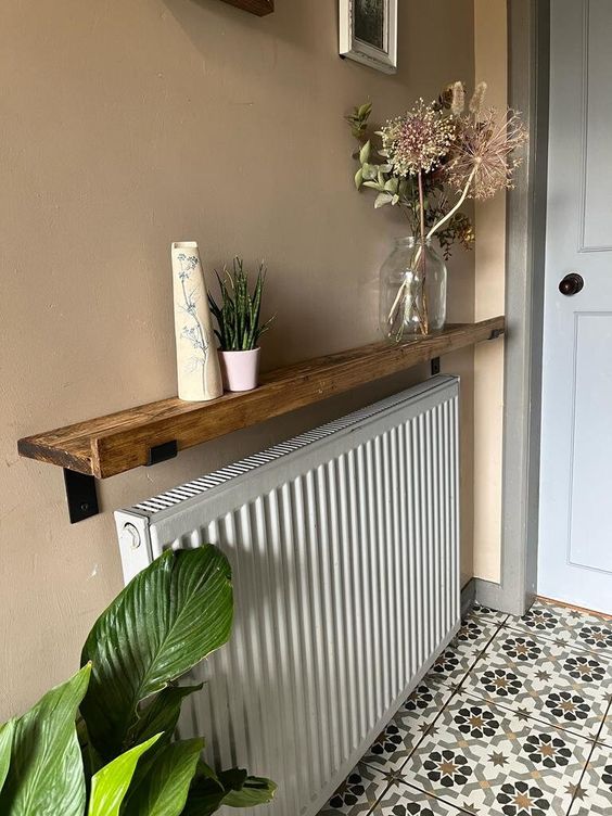 a radiator covered with a stained ledge used for decor displaying is a cool idea for any modern home