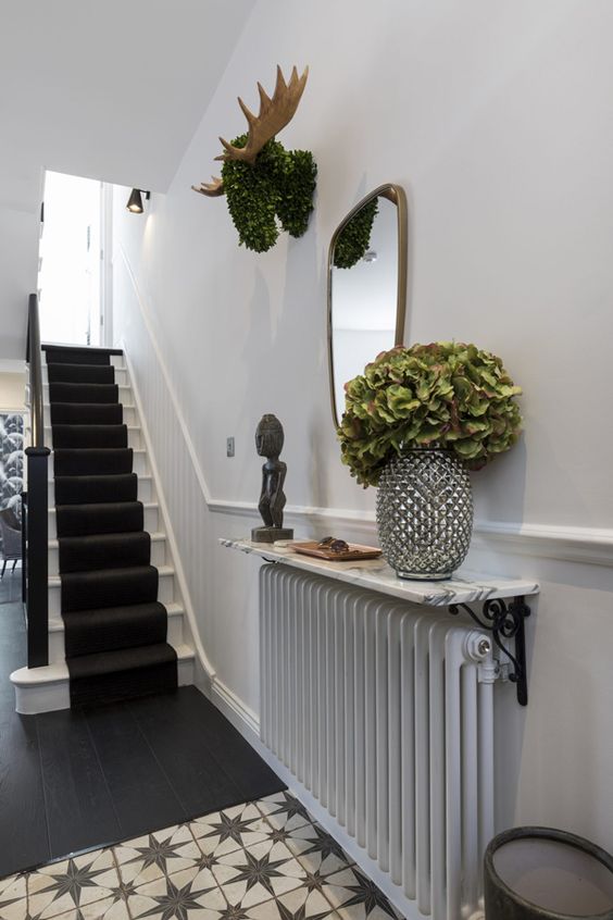 a radiator with a stone shelf over it, with decor and some greenery in a vase is a cool idea for a small entryway