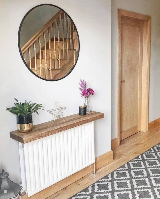 a white radiator with a stained shelf over it, with blooms, plants and decor is a cool idea for a Scandinavian space