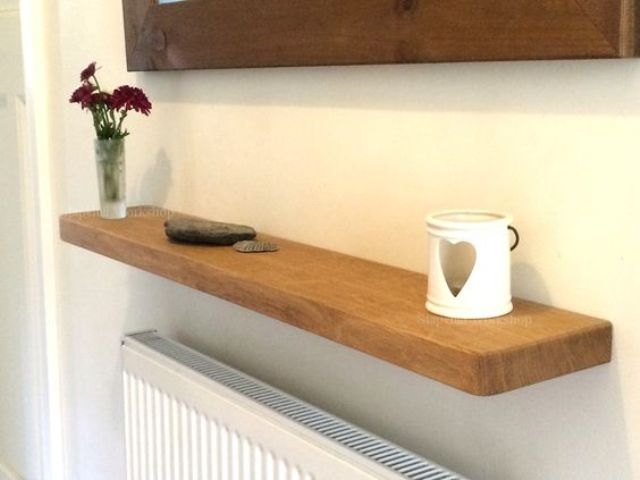 a soild oak floating shelf installed over a radiator is a cool idea for a hallway, where there's always not enough storage space