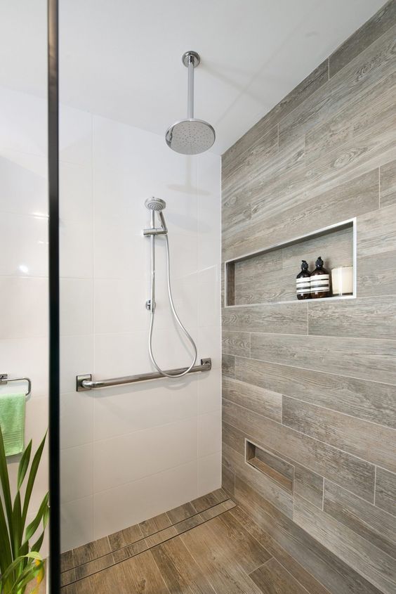 a lovely bathroom with wood tiles and a niche and a matching floor in the shower space to add an eye-catching touch