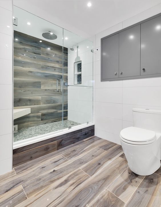 a minimal bathroom with wooden tiles and large scale white ones, a shower space, grey cabinets and white appliances