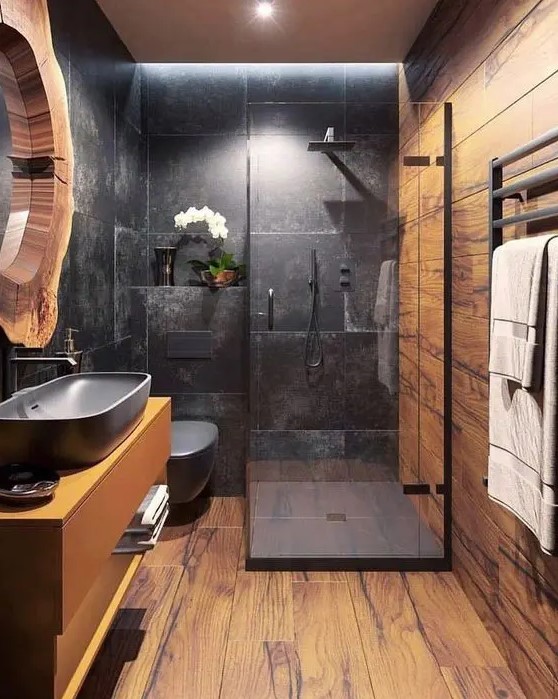 a stylish contemporary bathroom done with laminate, with a shower space done with black tiles, a floating vanity and a mirror in a wood slice frame