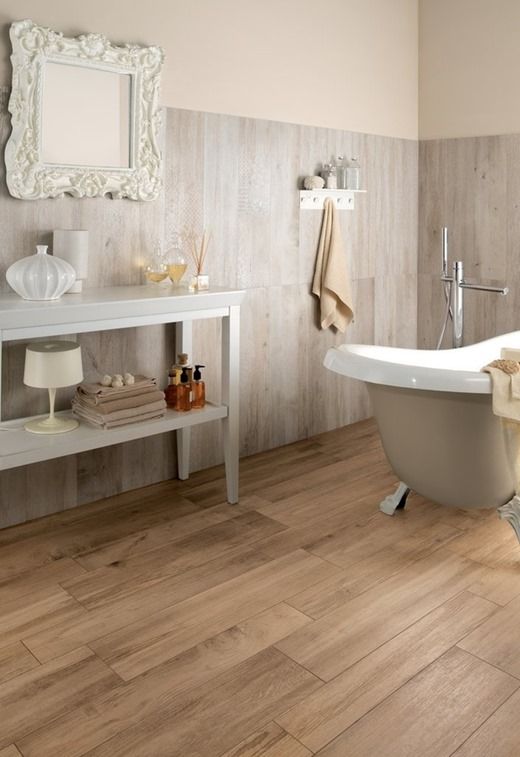 a vintage bathroom with wooden floor and wood-inspired tiles on the wall, a console table, a clawfoot bathtub