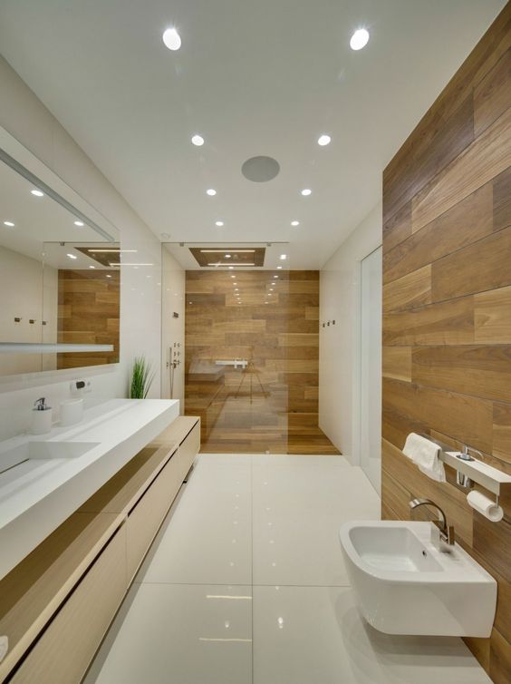 a minimalist bathroom with white large scale tiles and wood look tiles in the shower space and an accent by the toilet