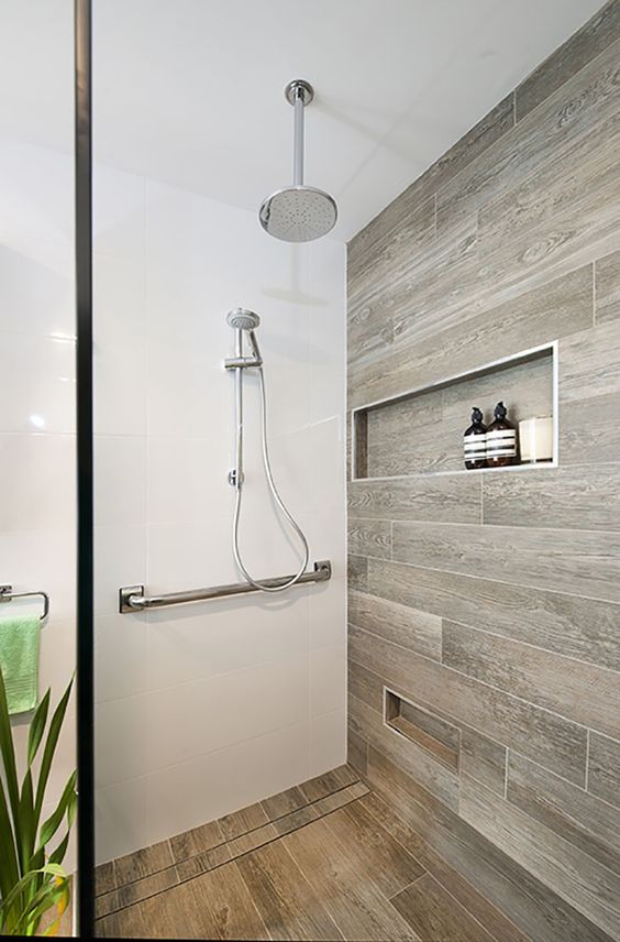 a minimalist bathroom with white surfaces and wood look tiles on the wall and floor for a warm feel in the space
