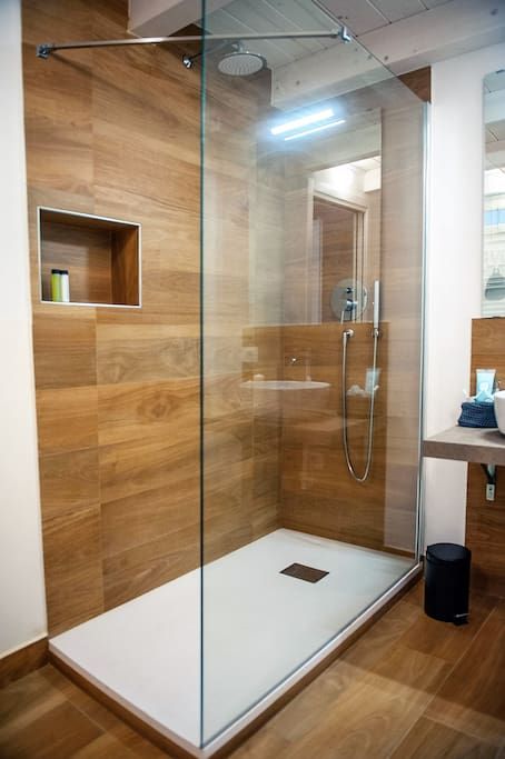 a minimalist bathroom done with warm wood look tiles and some white surfaces to refresh the space