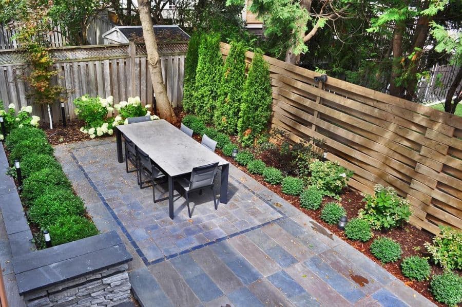Large terrace with slate tiles, garden furniture, wooden fence, green garden 