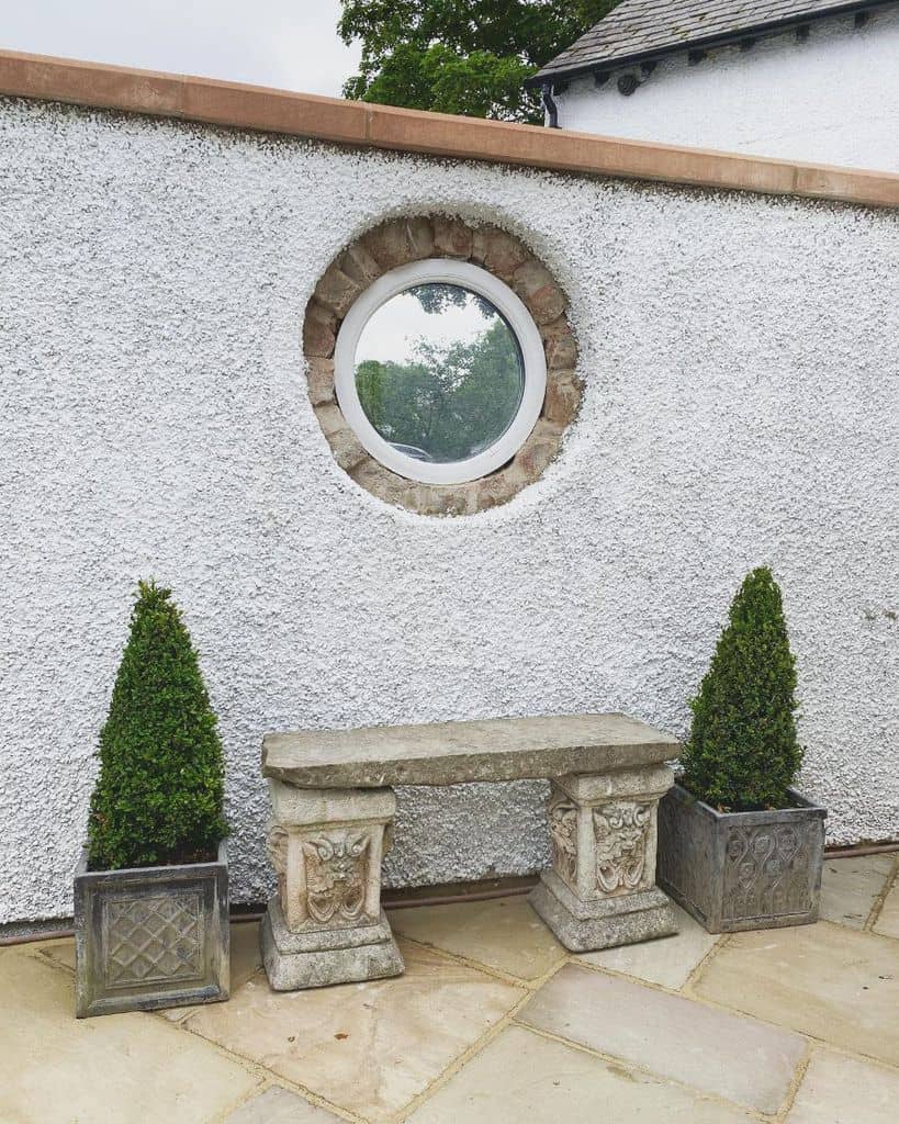 Stone seat with stone planters, textured wall with circular window 