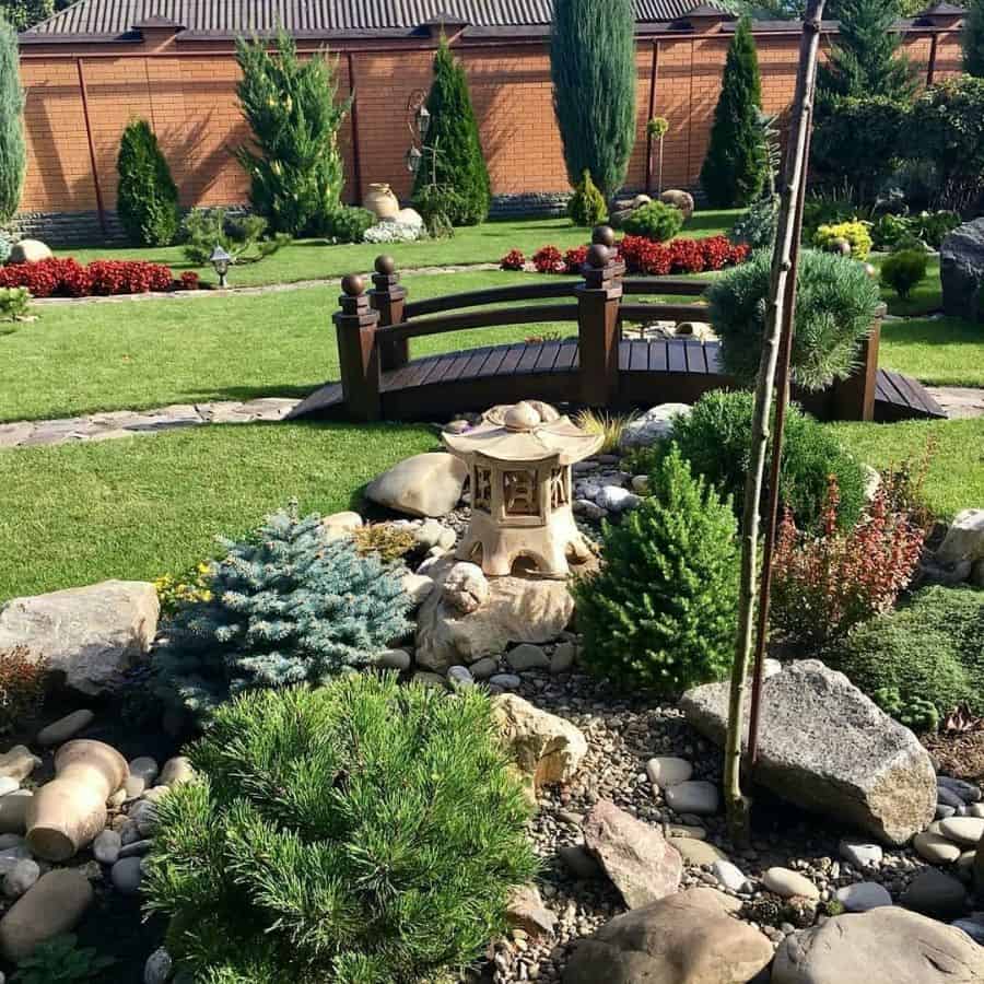 Asian style backyard, small wooden bridge, garden statue, green lawns 