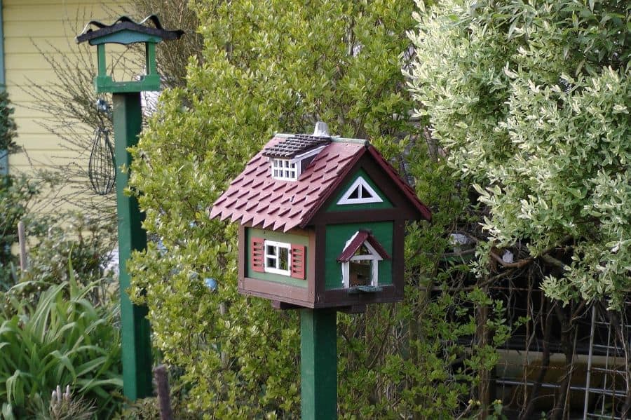 Birdhouse in the shape of a house on a green pole